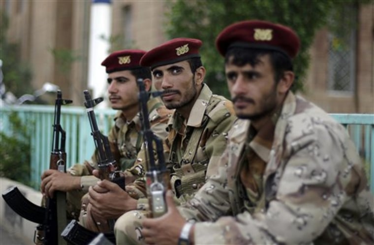 Yemeni army soldiers rest as they guard a street next to the site of a meeting Wednesday to elect a national council, in Sanaa, Yemen.